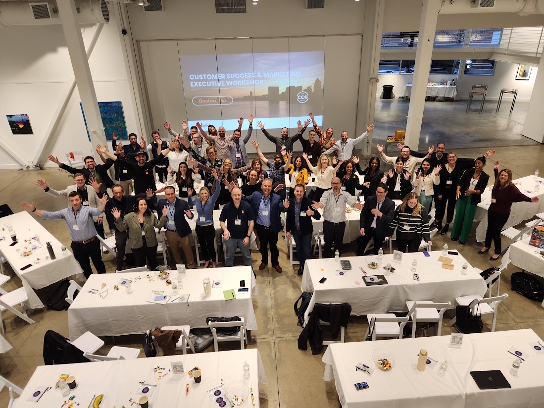 Dozens of Customer Success and marketing executives with arms raised at a CCO Club workshop in Boston