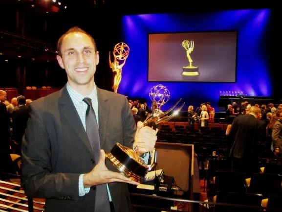 Josh smiling and holding an Emmy award in the auditorium after the ceremony